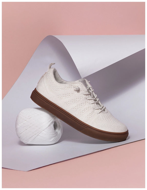 White sneaker with brown sole on a light pink background