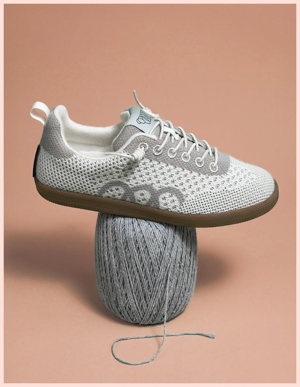 White and gray sneaker on a mushroom-shaped block with yarn, against a brown background