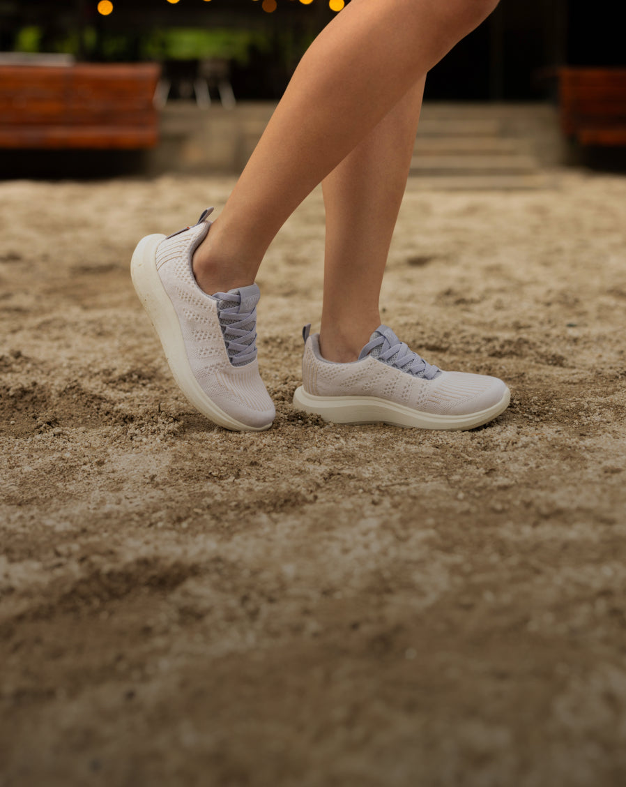 Close-up of a person walking outdoors wearing white and lavander Woolloomooloo sneakers with white sole